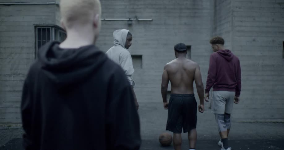 A group of men walk away and then one aggressively throws a ball at another man