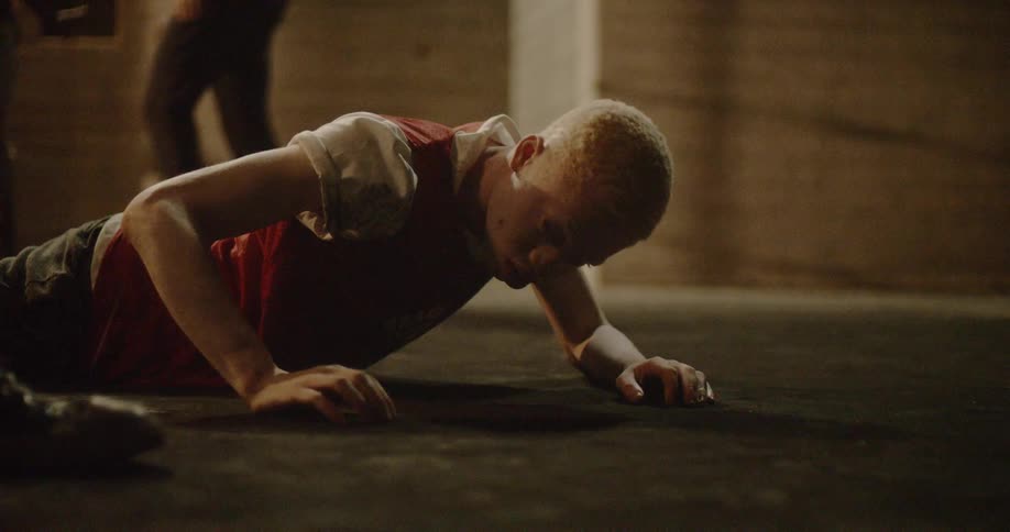 A young male tries to get up off the ground as others walk around him