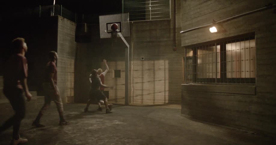 Four people play basketball together at night