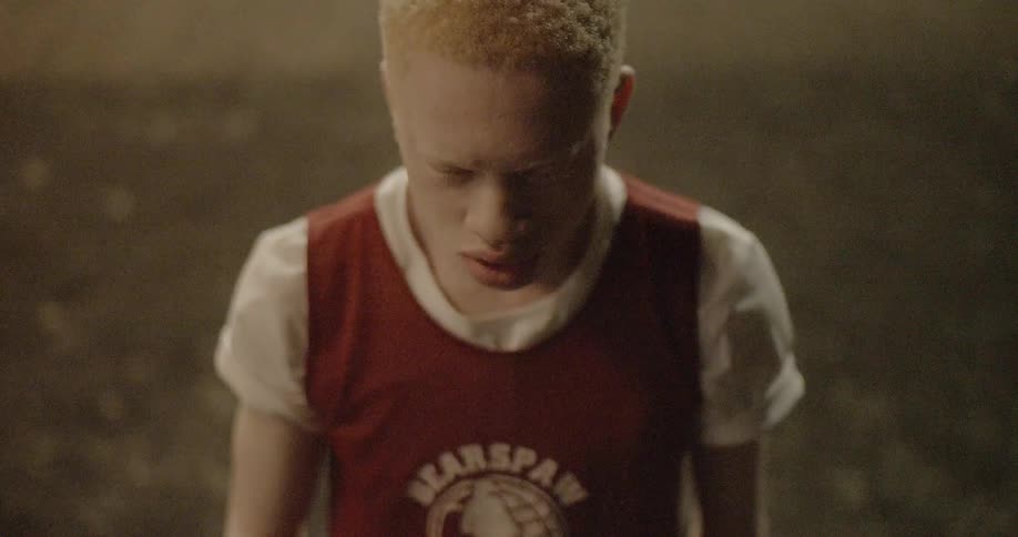 A teenager touches his nose and then throws a basketball