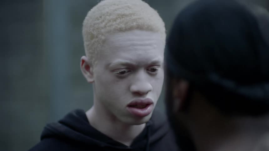 A teenager shakes his head in fear as a man yells and pushes him
