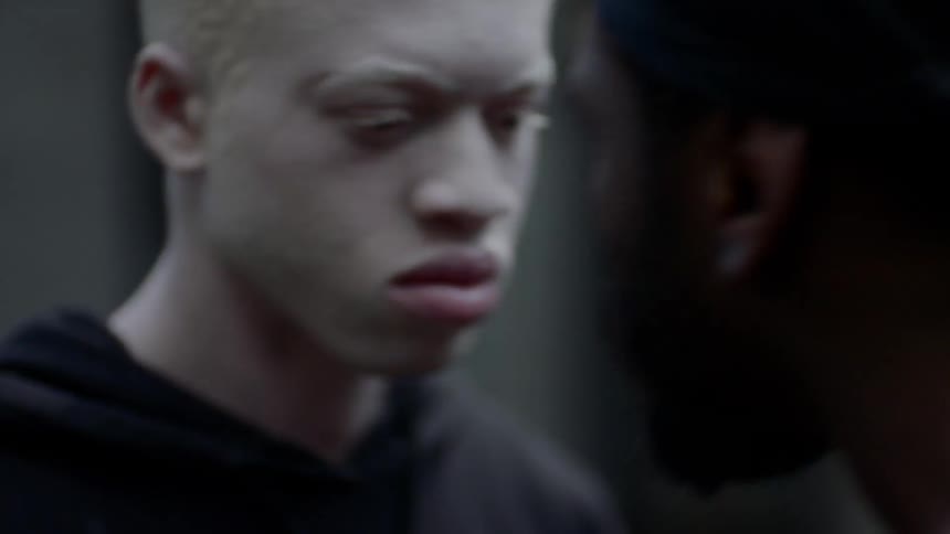 Two men stand face to face looking angry then one shoves the other
