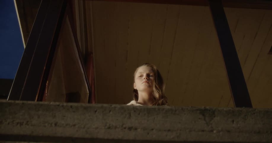 Young woman looks out window at night