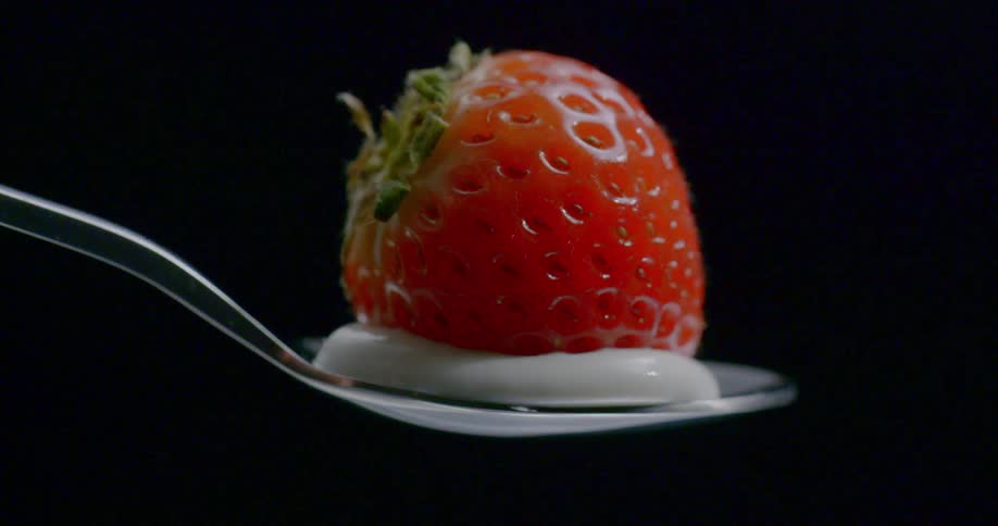 A strawberry on top of yogurt