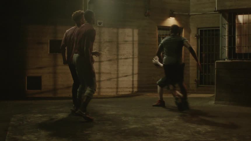 Teenagers play basketball in a concrete courtyard