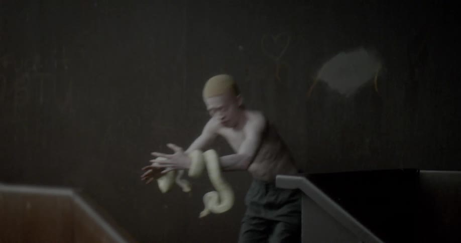 An albino man holding a basketball is shocked to find he has two white snakes wrapped around his wrists