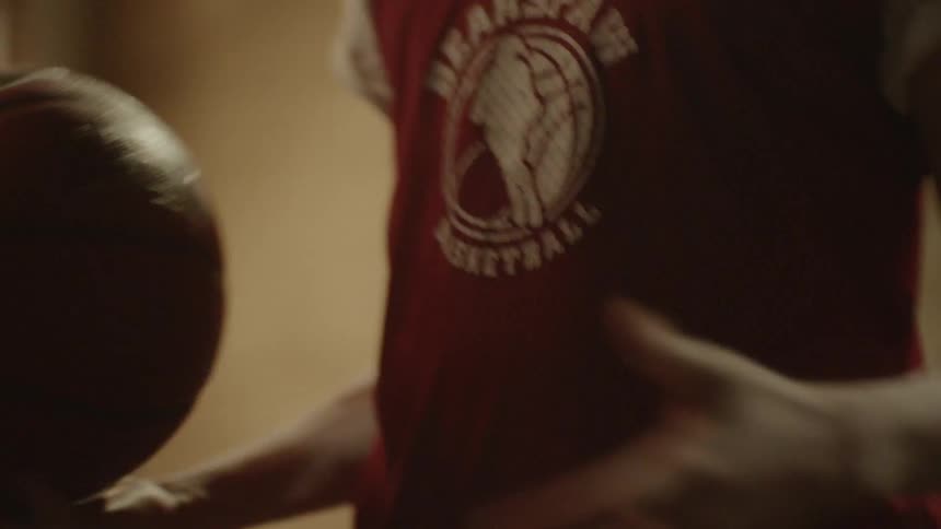 A basketball player swaps a basketball between his hands