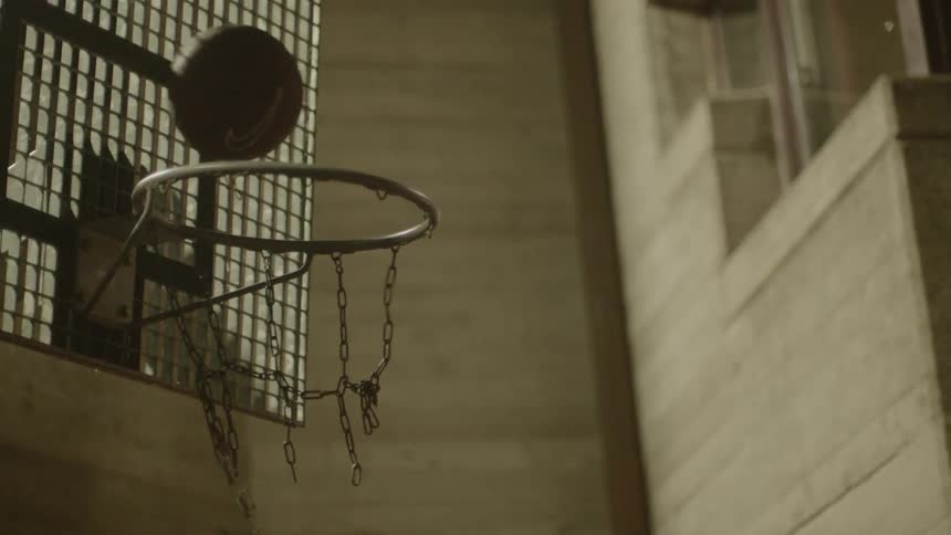 A basketball goes through a dilapidated hoop