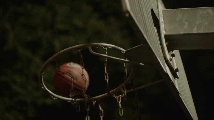 A basketball bounces off the rim of a basketball hoop outside at night