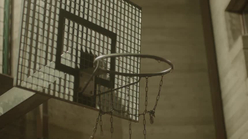 A basketball flies in to the hoop with a broken chain net