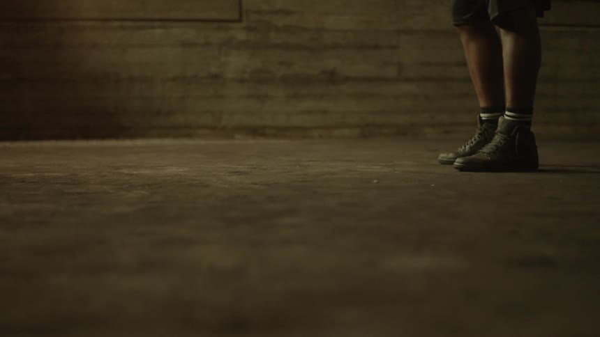 Man dribbles basketball on concrete near building wall