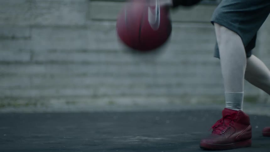 A man picks up a basketball and dribbles