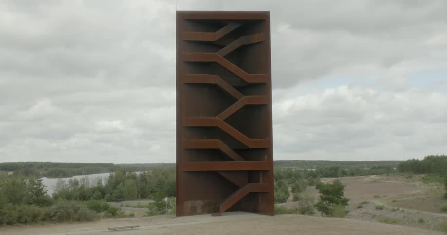 Staircases lead up and down a many storied open framed structure near river