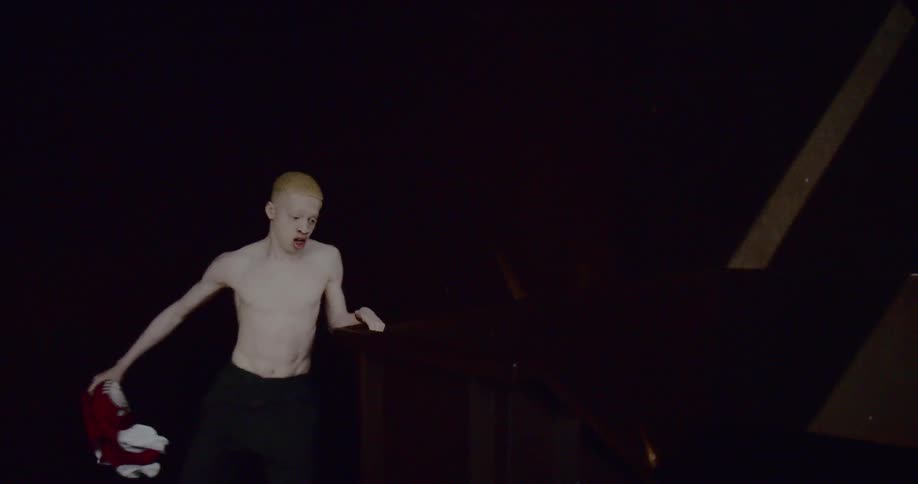 Young albino black man runs through industrial building