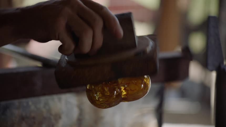 A glassblower works on a piece of art