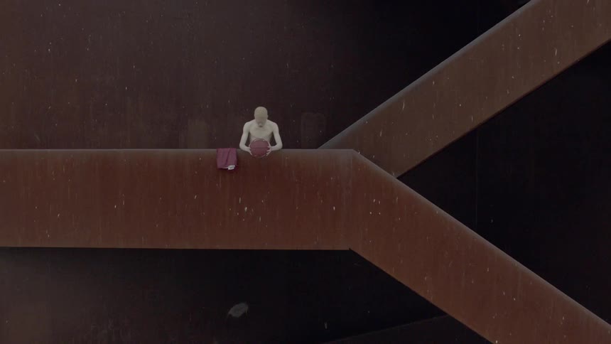 Man painted in white holds a basketball over the ledge of a staircase on building