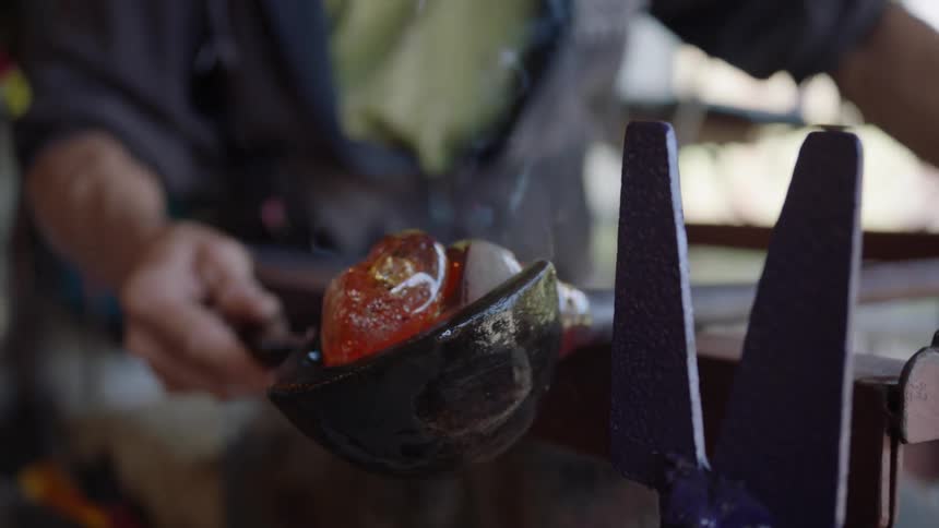 A man rolling a bar with molten glass on the end
