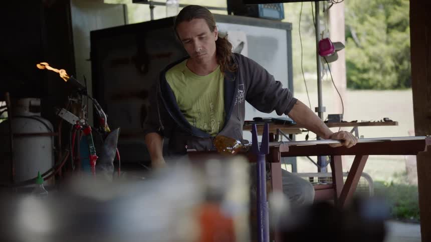 A man is working in his shop outside spinning glass