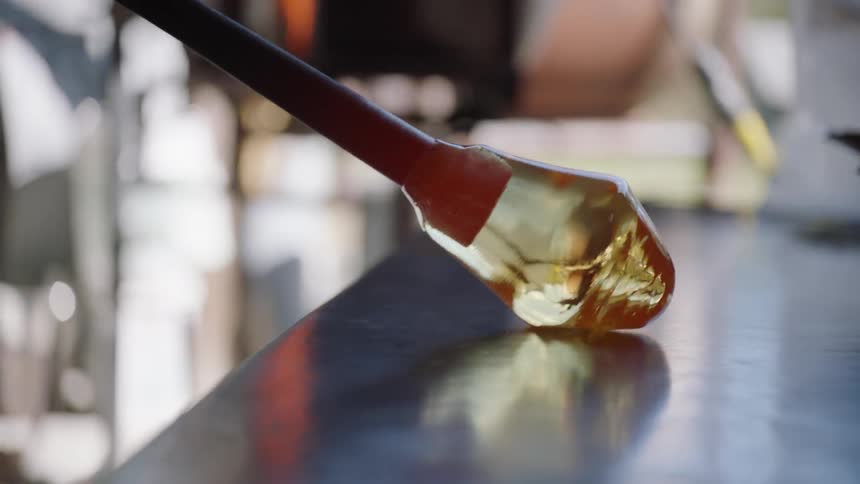 A glassblower sculpts a hot glob of glass