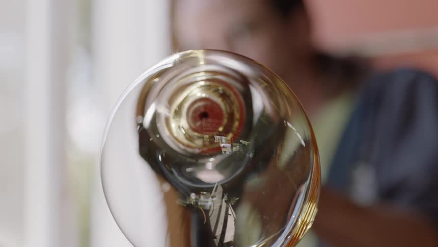 Man blowing a bubble of molten glass through a metal rod