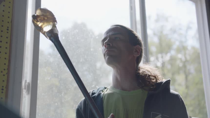 A man holds a long pole with blown glass at the end of it