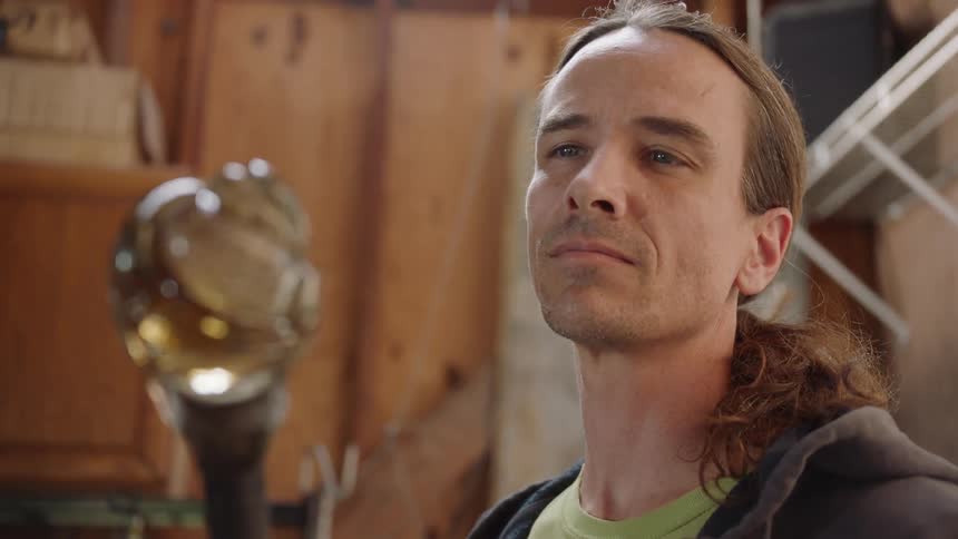 Long haired man contemplates crystal ball on top of staff