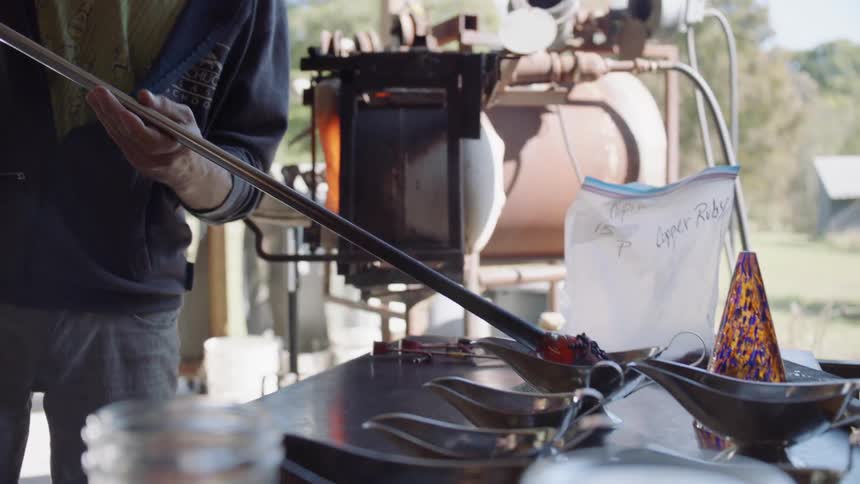 A young man heats up glass before glass blowing