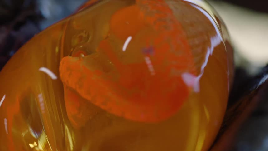 A glassblower works a hunk of hot glass