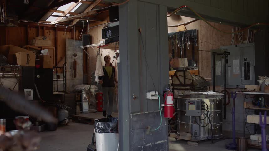 A man carrying a stick walks in his shop