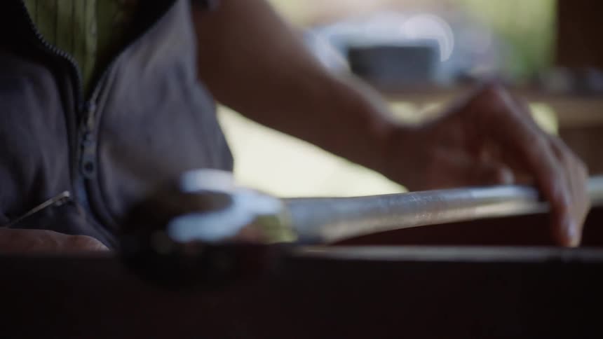 A man rolls molten glass on an iron rod