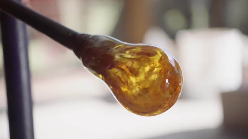 A person spins a rod forming glass