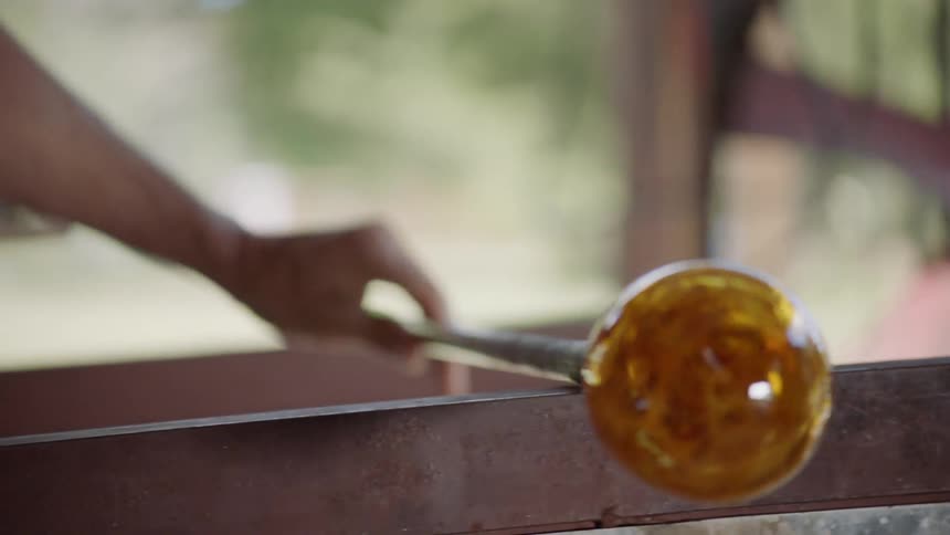 Glassblowers work on a hot glob of glass