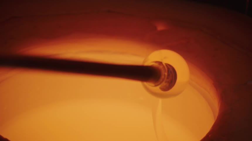A poll being pulled out of molten glass