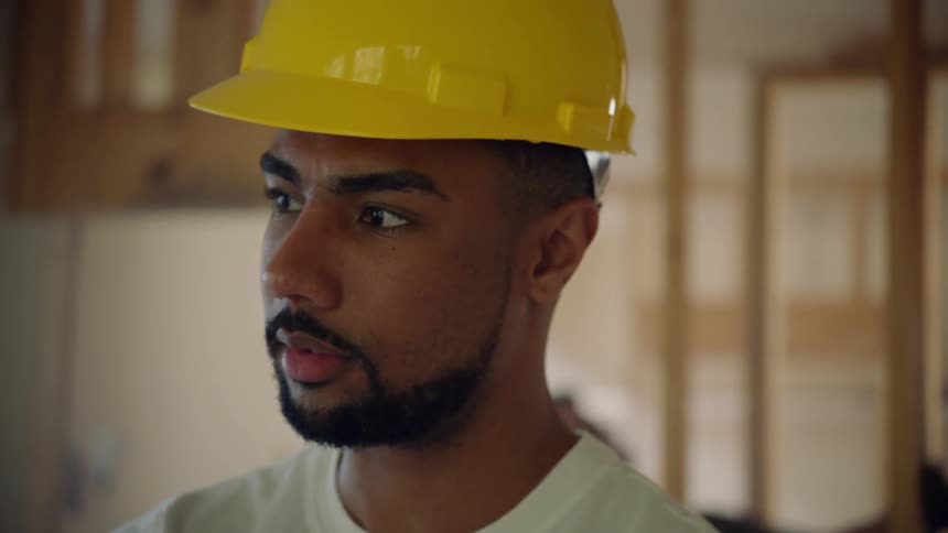 A man in a hard hat nodding his head at a construction site