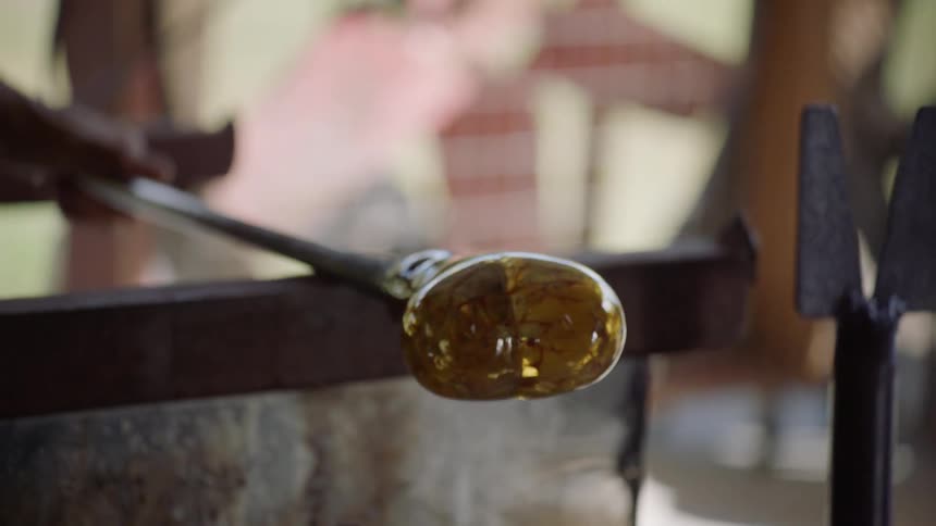 Man rolls a craft on a long handle and buffs it with a sponge then creases it with a knife