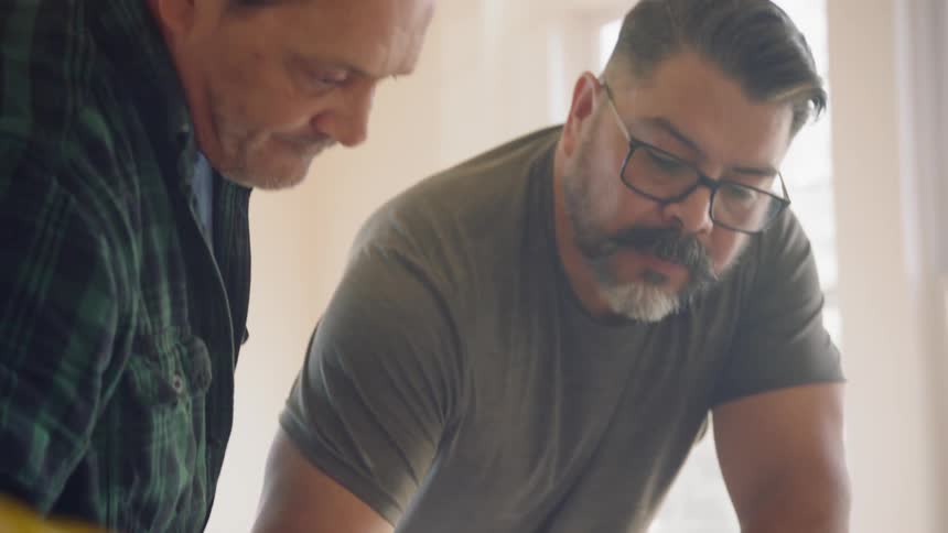 Two male contractors draft up plans for the work they are going to do