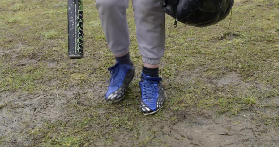 A person in blue shoes drops a bag full of baseballs in the rain