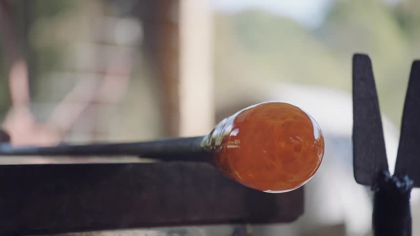 A blacksmith using a tool to mold a round end on a metal staff