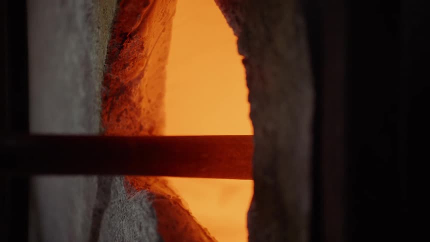 Glass being turned on a metal rod inside a furnace