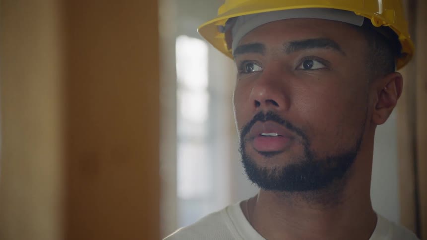 A man in a hard hat looks at a beam in a building