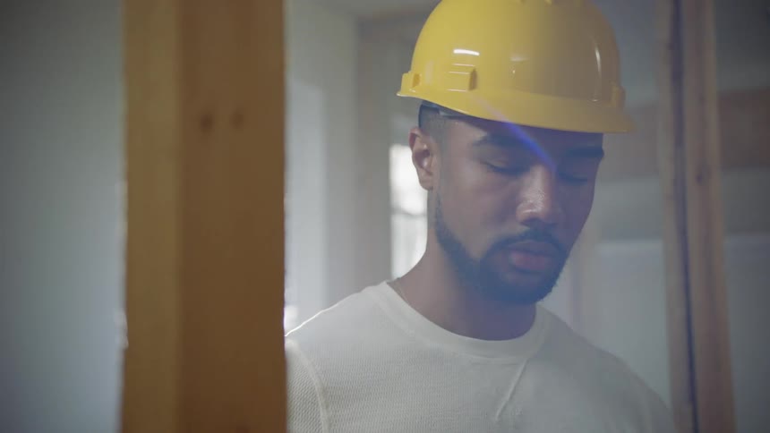 A construction worker in a hard hat stands in a room