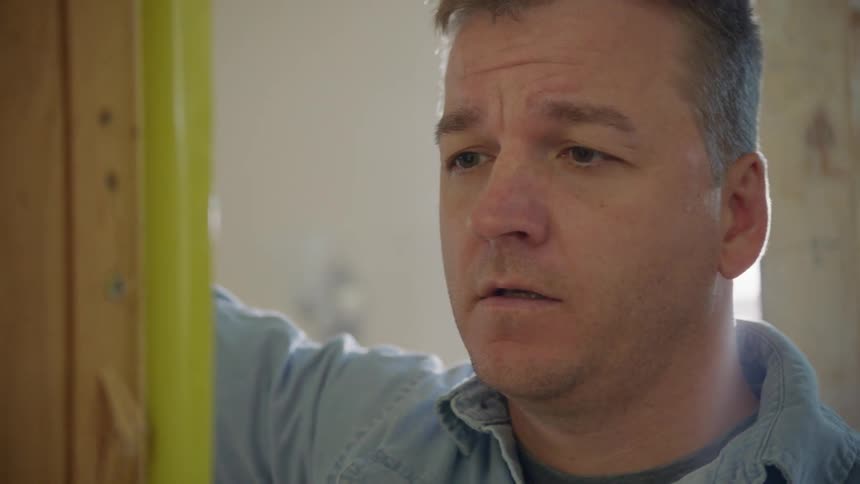 A white man examines a measuring tape