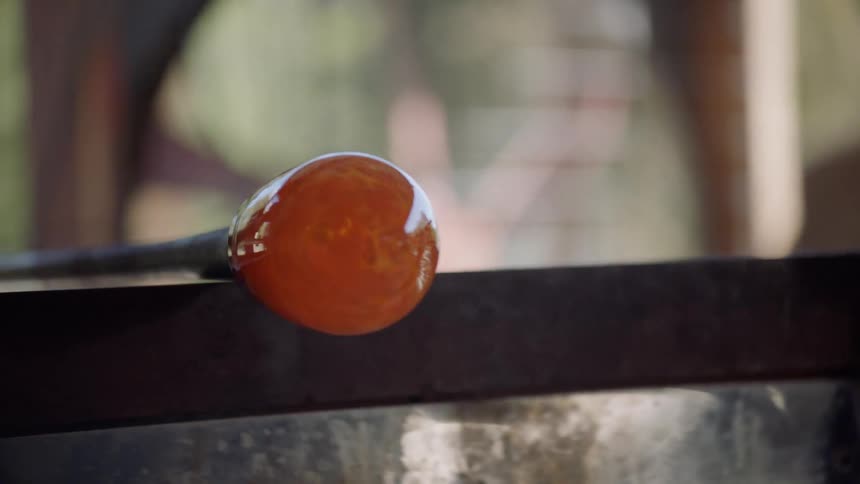 Molten glass being rolled on a metal rod