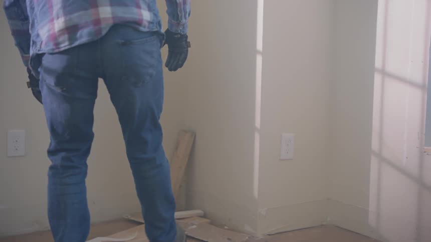 A man walks across a room and picks up building scraps
