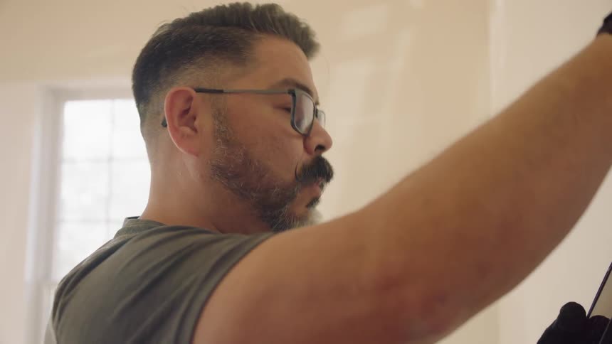 A man compares blueprints on a wall to his tablet