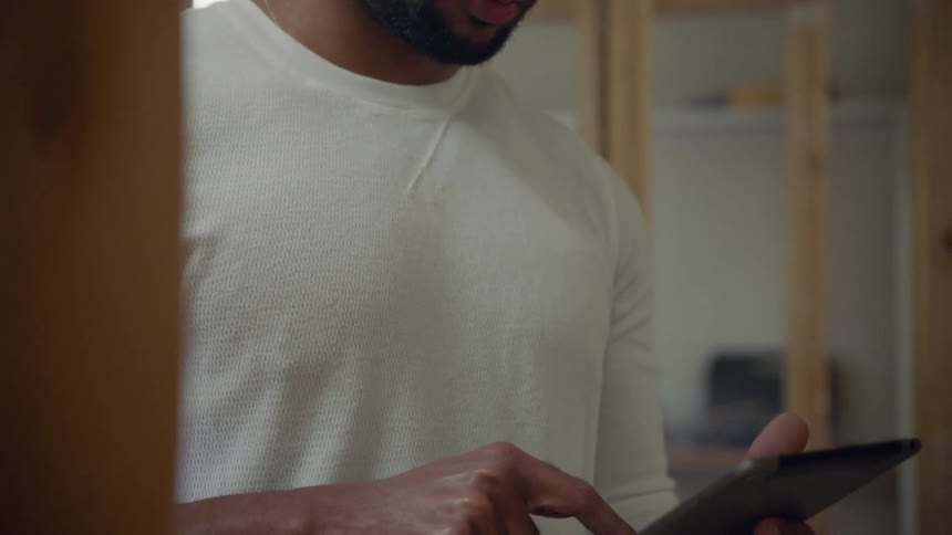 Man wearing hard hat enters data on tablet at construction site
