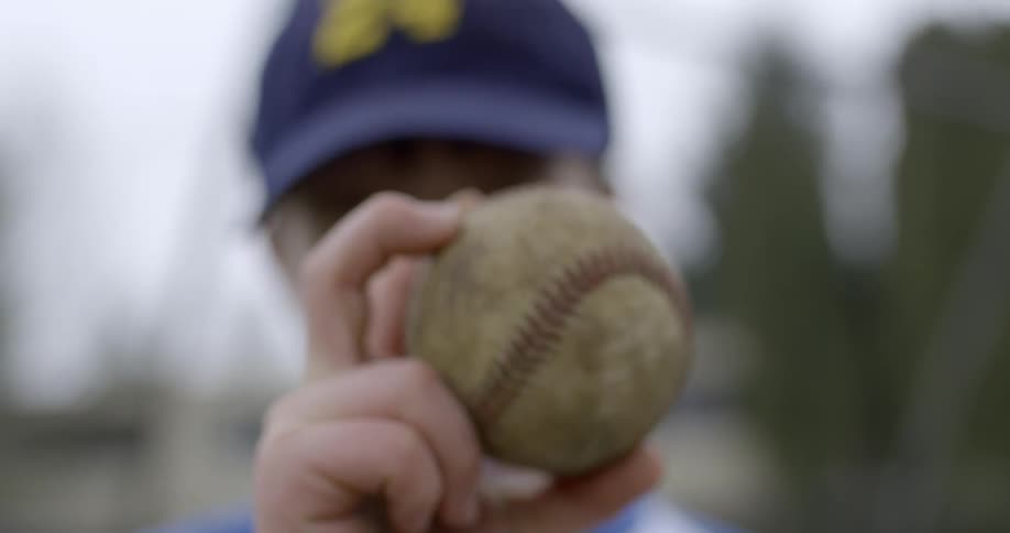 A boy holds a baseball outside