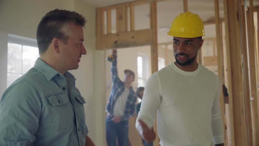 Two construction workers talk and shake hands on a construction site