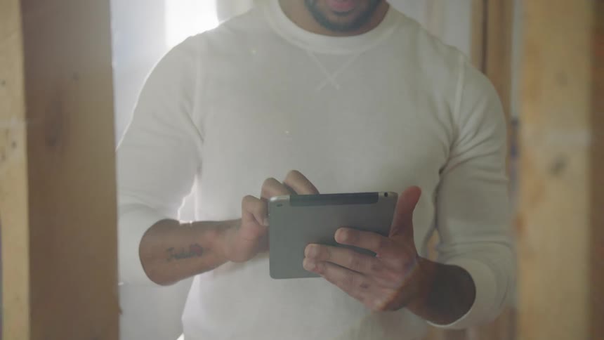 Construction worker wearing hard hat takes notes on tablet
