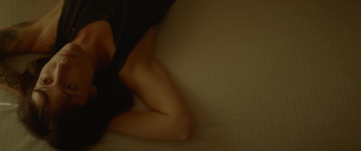 Woman relaxing on bed while shadow of blinds sway in the breeze